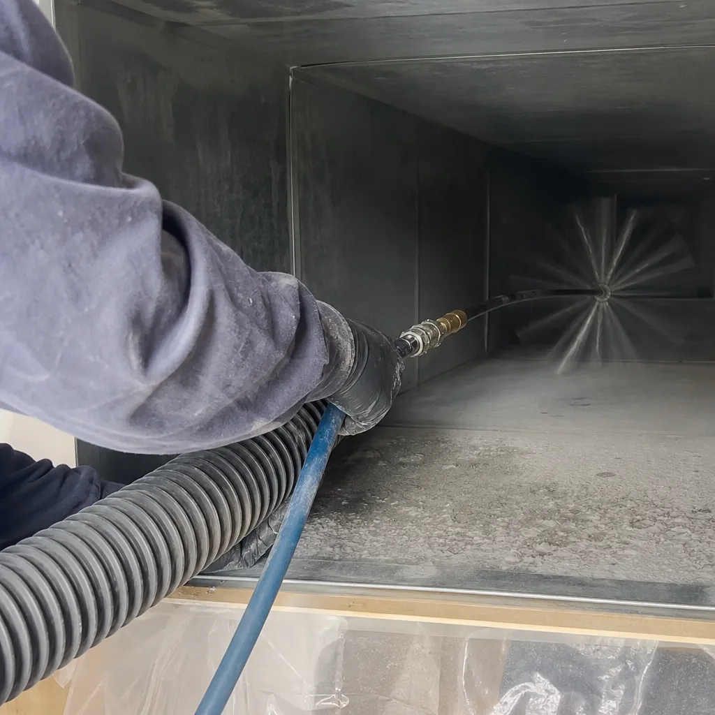 Technician using a rotating brush tool for professional air duct cleaning
